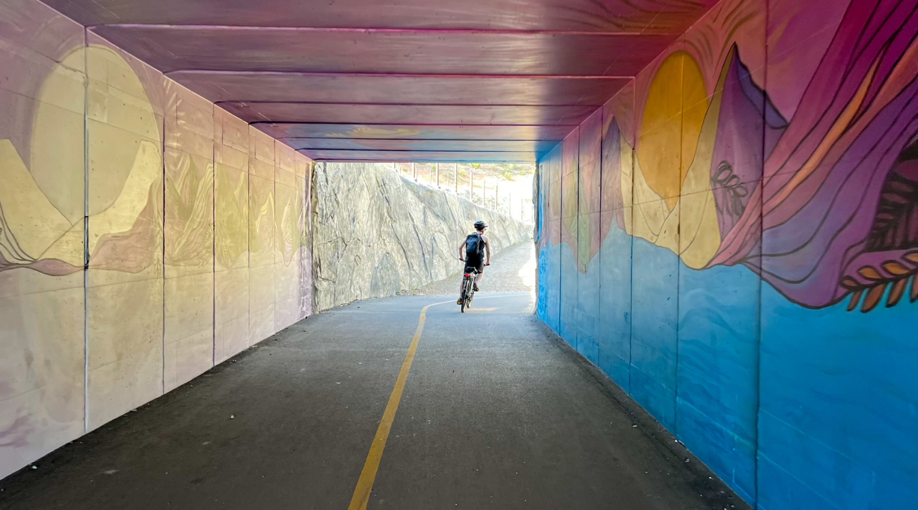 Person biking under decorated road underpass