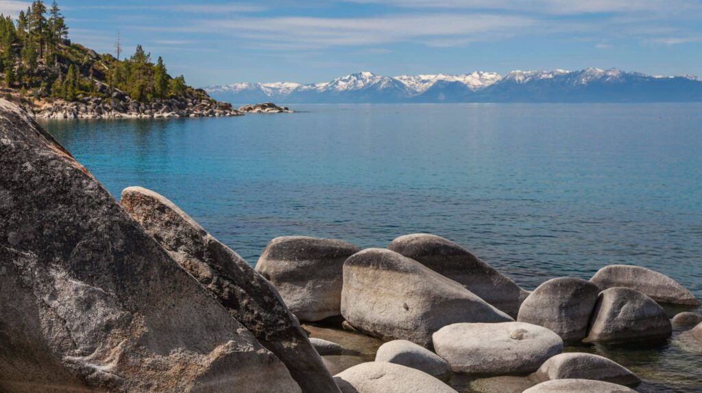 large rocks on sand harbor beach with lake tahoe in the background